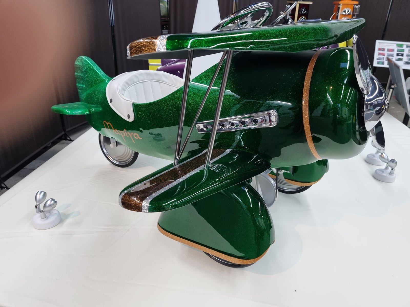 Auf einem weißen Tisch steht ein grünes Spielzeugflugzeug.